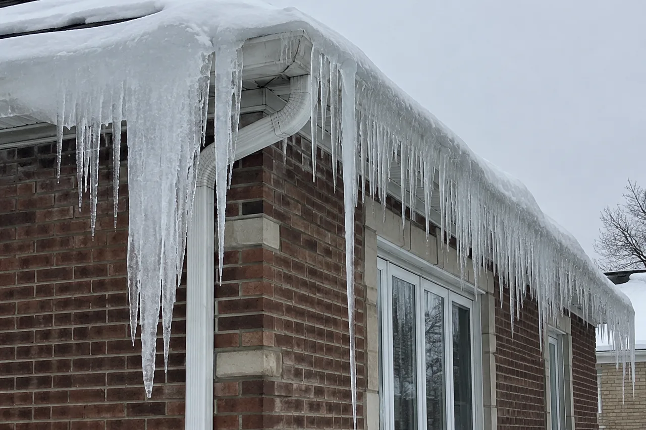 Thick ice dam and long icicles along the roof edge and gutter of a brick Chicag… Thick ice dam and long icicles along the roof edge and gutter of a brick Chicago bungalow after a snowstorm