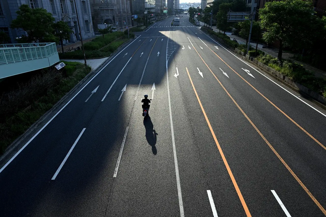 Motorcyclist riding down a wide, empty city street